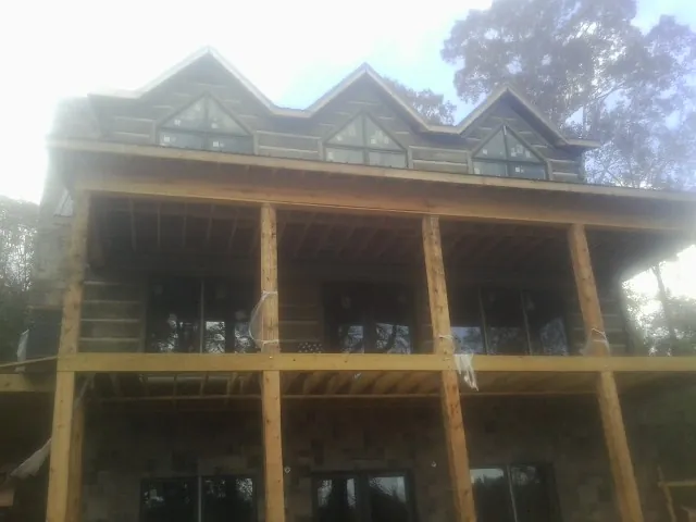 Dormers and porch framing on a large log home under construction — Roof Coating work by our crew in Slidell